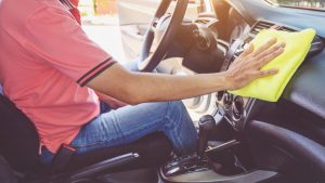 Person cleaning dashboard with microfiber towel