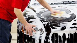 Car being washed with a hose and sponge